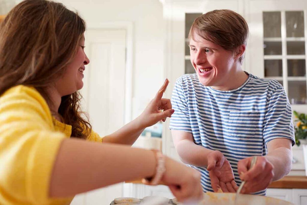 A person with development disabilities cooking with a caregiver