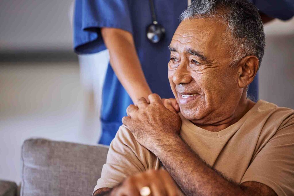 A senior man smiling touching the hand of his home health care worker