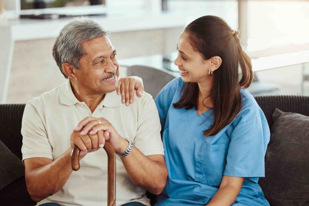 Home health aide sitting with an older man and providing support at home