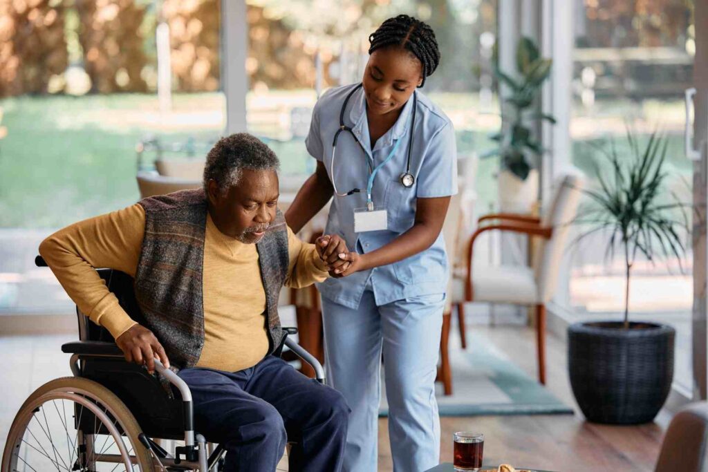 Home health caregiver assisting elderly man in wheelchair with mobility support